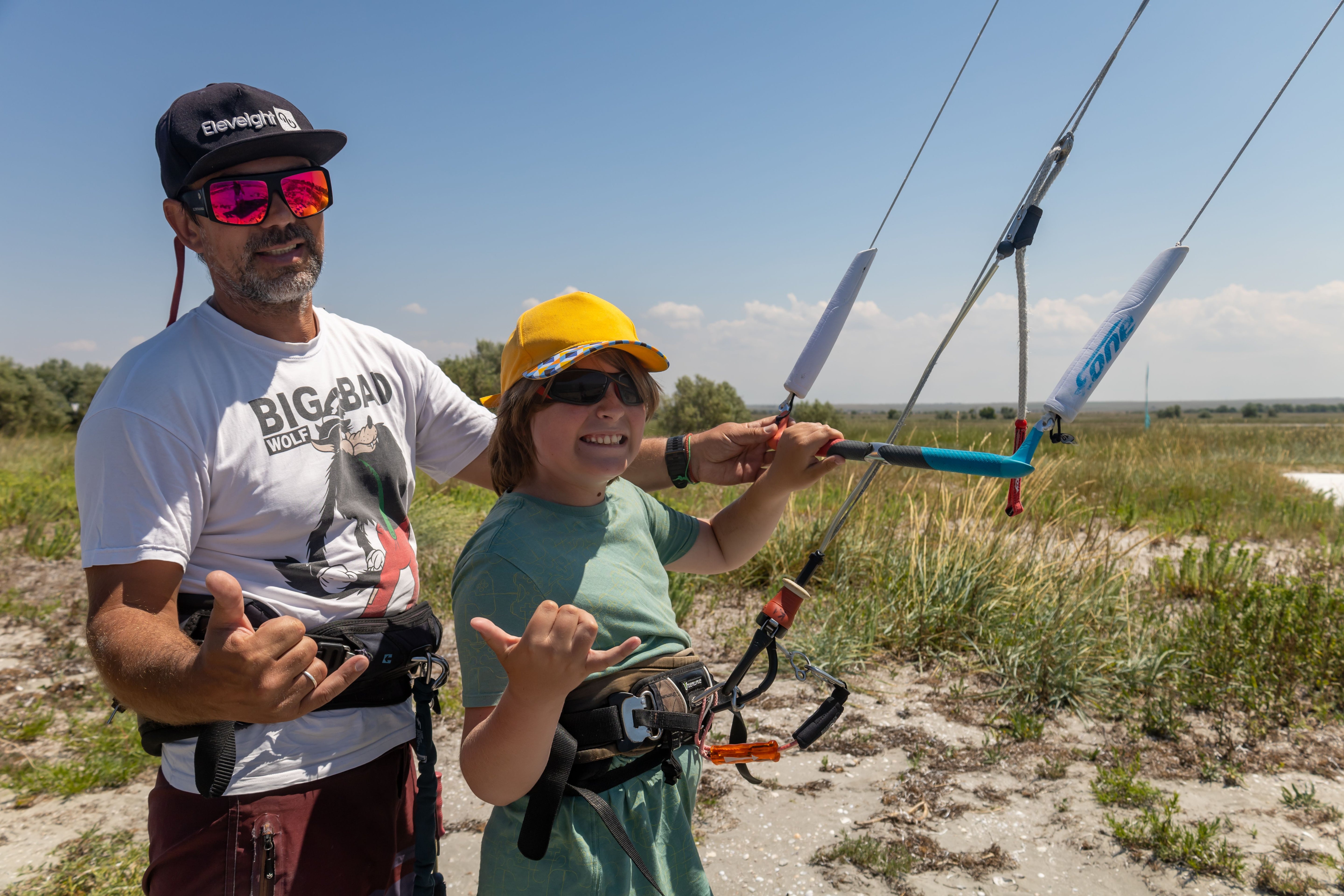 Vader en zoon maken zich klaar om te kitesurfen, shaka-teken